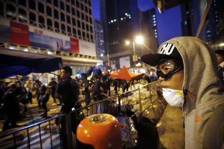 A pro-democracy protester looks on as policemen remove a barricade at a protest site in Mongkok shopping district in Hong Kong October 17, 2014. REUTERS/Carlos Barria