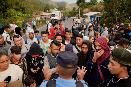 A police officer (back to camera) calms down migrants waiting permission to cross the border between Honduras and Guatemala towards the United States, in Agua Caliente, Honduras, January 16, 2019. REUTERS/Alexandre Meneghini