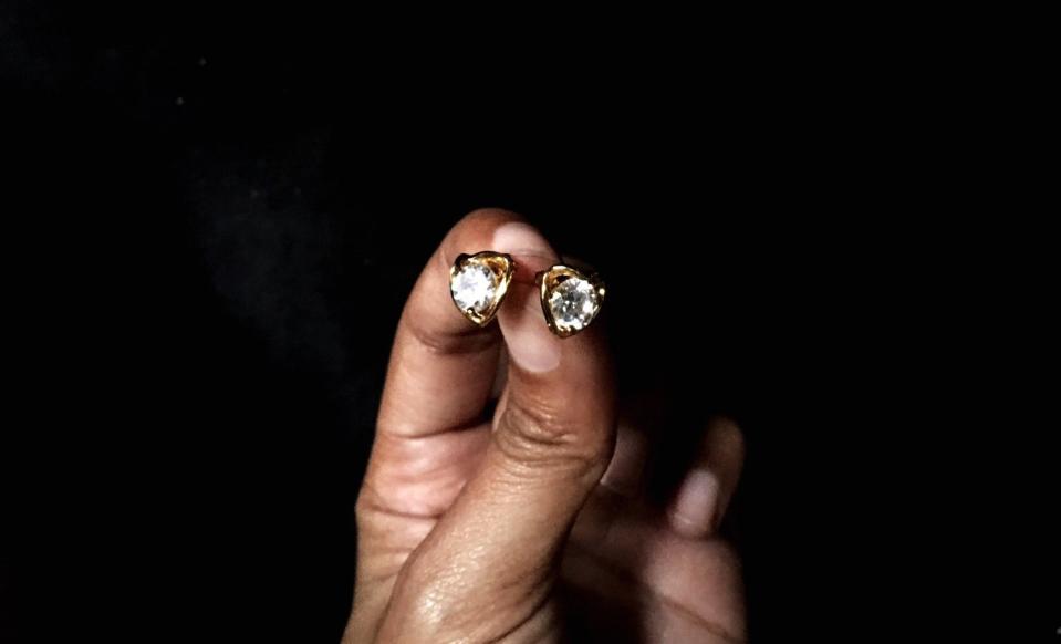 a person's hand holding diamond earrings