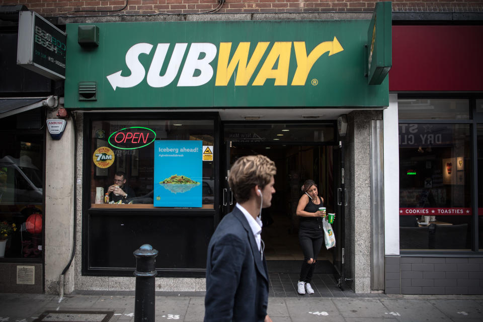 Eine Frau verlässt einen Subway-Laden in London, England, als ein Mann vorbeiläuft.