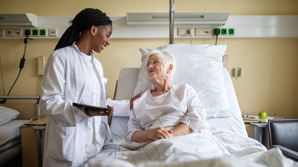 An older female in a hospital bed with a healthcare professional