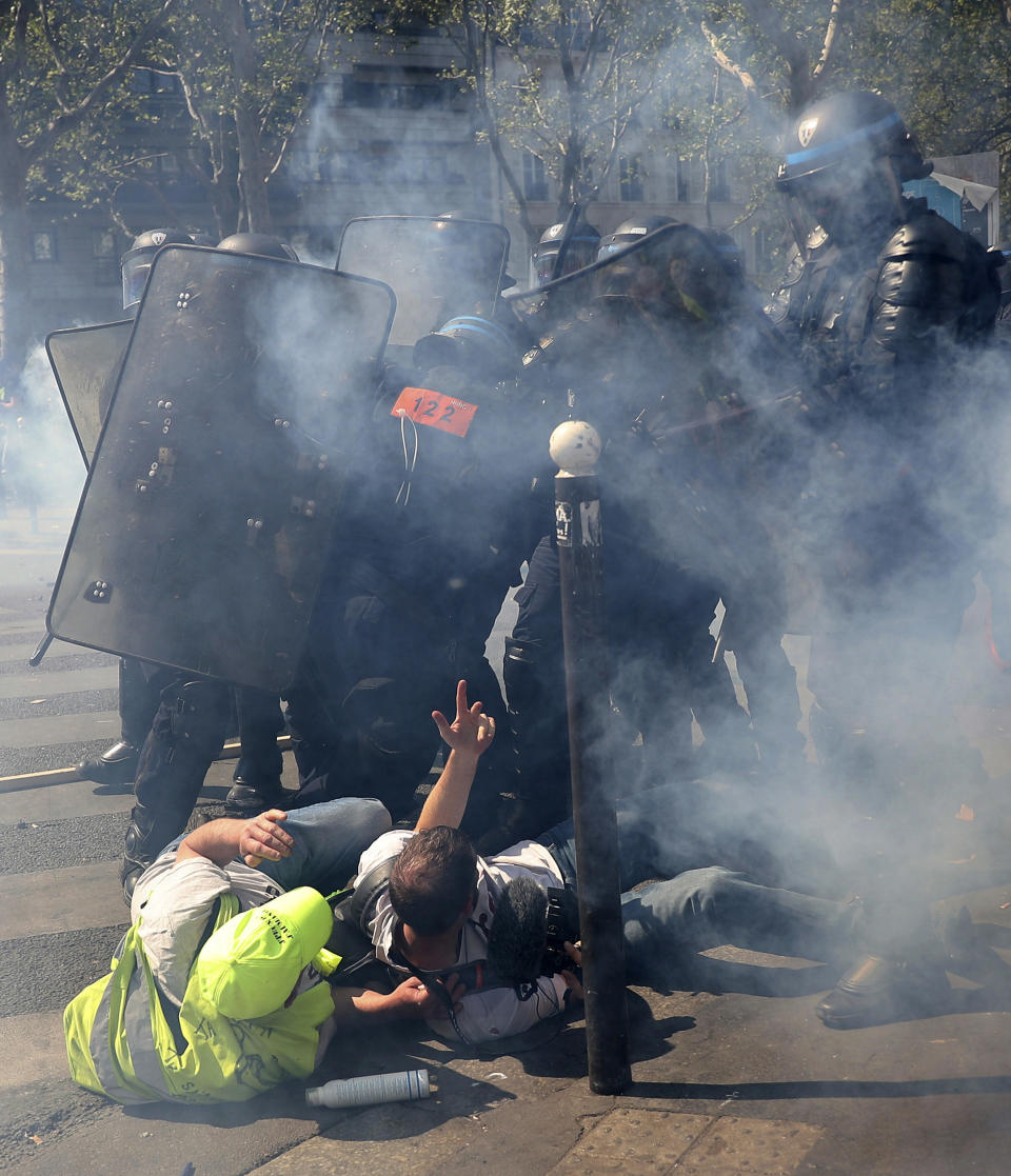 Police advance on protestors during a yellow vest demonstration in Paris, Saturday, April 20, 2019. French yellow vest protesters are marching anew to remind the government that rebuilding the fire-ravaged Notre Dame Cathedral isn't the only problem the nation needs to solve. (AP Photo/Francisco Seco)