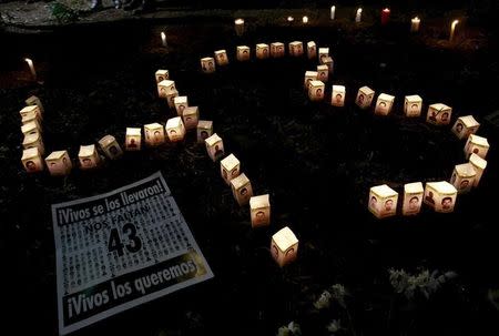 Candles burn beside pictures of some of the 43 missing students, on the six-month anniversary of their disappearance, during a vigil outside the office of Mexico's Attorney General in Mexico City, March 26, 2015. REUTERS/Henry Romero