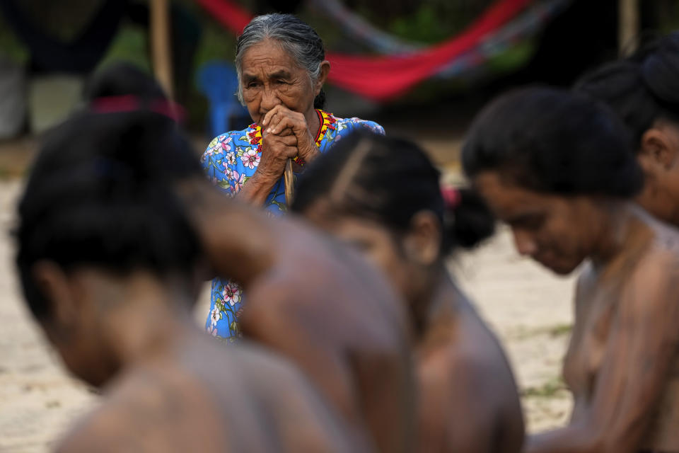 Elder Santana Tembé observan mientras pintan el cuerpo de las niñas durante el rito de madurez Wyra'whaw, en el centro ritual Ramada, en la aldea Tenetehar Wa Tembe, en la tierra indígena Alto Río Guamá, en el estado de Pará, Brasil, el 10 de junio de 2023. (AP Foto/Eraldo Peres)