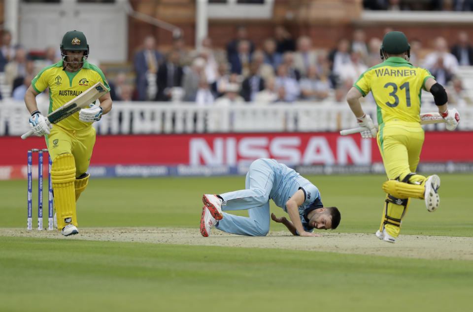 England's Mark Wood goes to ground after pitching a delivery as Australia's captain Aaron Finch, left, and Australia's David Warner add runs during the Cricket World Cup match between England and Australia at Lord's cricket ground in London, Tuesday, June 25, 2019. (AP Photo/Matt Dunham)