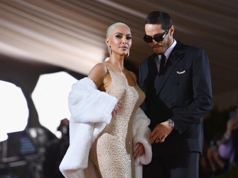 kim kardashian and pete davidson standing together at the met gala, with kardashian looking outwards and davidson looking slightly down at her, wearing sunglasses