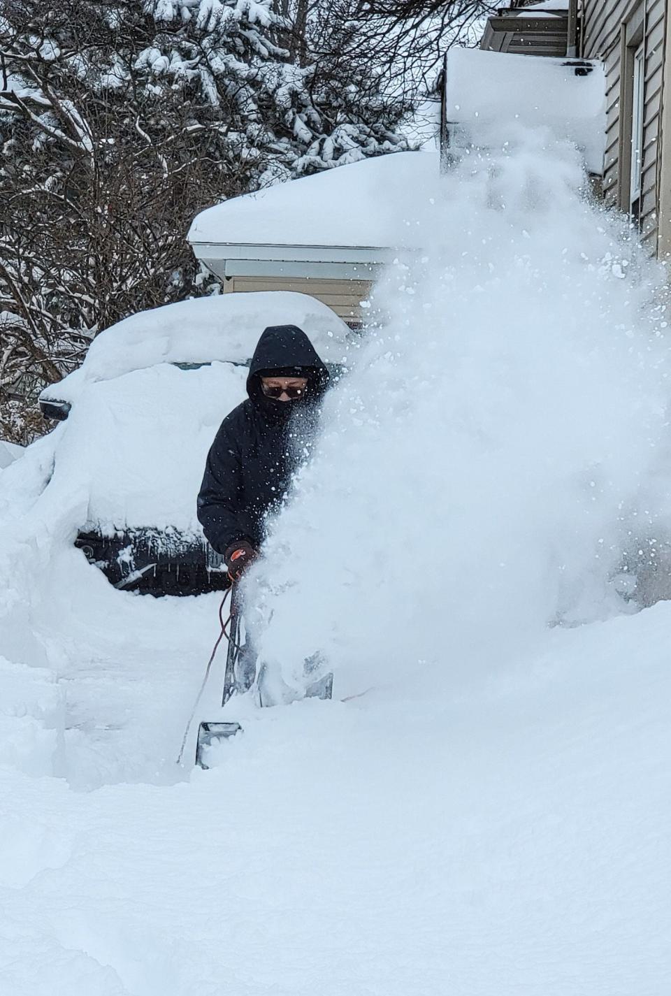 Quentin Wyatt uses his snow blower to dig out of his driveway Monday on Rose Avenue in Akron.