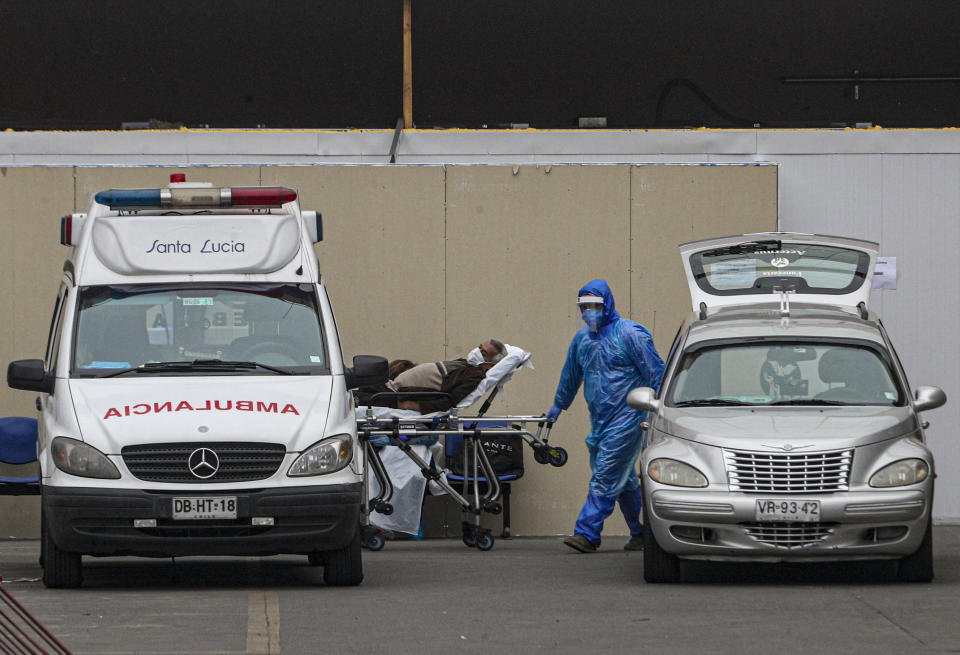 Trabajadores de salud usan equipo de protección contra el coronavirus mientras mueven a un paciente entre una ambulancia y una carroza funeraria el miércoles 17 de mayo de 2020, en el hospital San José en Santiago, Chile. (AP Foto/Esteban Félix)