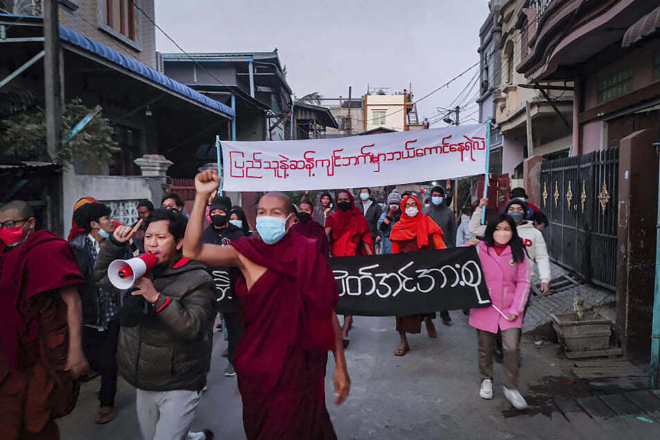 Youth activists and Buddhist monks participate in an anti-military government protest rally while holding a banner that reads in Burmese, "Who dares to stay on the opposite side of the people's will," on Tuesday, Feb. 1, 2022, in Mandalay, Myanmar. The new U.N. special envoy for Myanmar says violence has intensified since the military took power a year ago and sparked a resistance movement in the country. (AP Photo)