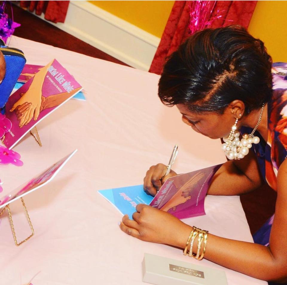 Nashville native Tiffany Burgess signs a copy of "Skin Like Me," her first published children's book (2016). Burgess, a graduate of MLK Magnet, appears in the 2023 film "The Color Purple."