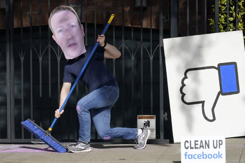 A man who did not give his name wears a mask of Facebook CEO Mark Zuckerberg as he and others demonstrate outside of Zuckerberg's home to protest what they say is Facebook spreading disinformation in San Francisco, Saturday, Nov. 21, 2020. (AP Photo/Jeff Chiu)