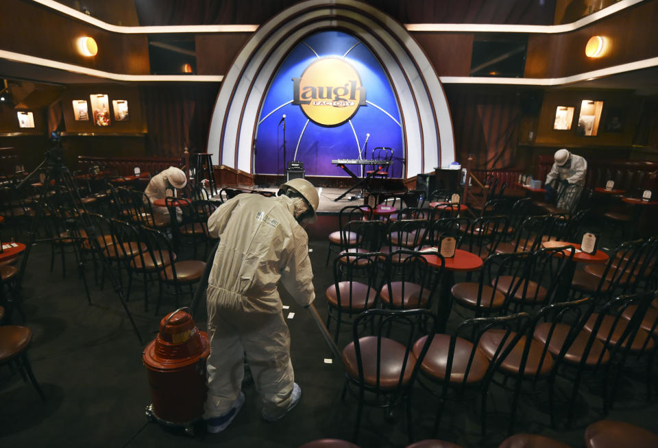 In this April 20, 2020, photo, crew technicians from ServiceMaster by ARS clean, sanitize and disinfect the Laugh Factory comedy club before a "Laughter is Healing" free stand-up comedy livestream event in Los Angeles. With comedy clubs closed and concert tours put on hold, comics like Craig Robinson, Tiffany Haddish, Will C and others are keeping the jokes flowing on webcasts and Zoom calls even without the promise of a payday, because they say the laughs are needed now more than ever. (AP Photo/Chris Pizzello)