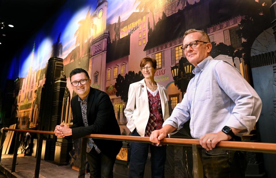 Three people stand inside a theater.