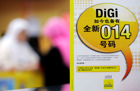 FILE PHOTO: An advertisement of Malaysia's DiGi.Com is displayed at a mobile phone shop in Kuala Lumpur May 4, 2006. REUTERS/Bazuki Muhammad/File Photo