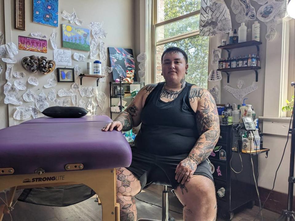 Cj Malone at Songbird Tattoo Studio posing next to their tattoo table in Bellingham.