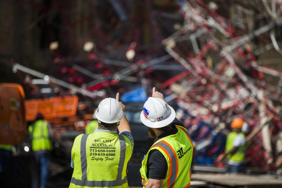 Construction workers begin cleaning up collapsed scaffolding on the 300 block of East Martin Street, Friday, Sept. 20, 2019 in San Antonio. Officials say three bystanders were slightly hurt as a 100-foot (30-meter) section of scaffolding collapsed on a San Antonio street amid 50 mph (80 kph) winds from a system linked to Tropical Storm Imelda. The scaffolding, along a high-rise building, crushed several parked vehicles and crashed into St. Mark's Episcopal Church. (Daniel Carde/The San Antonio Express-News via AP)