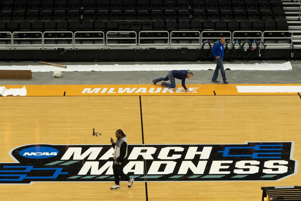 Workers install the court for the NCAA men's basketball regional games at Fiserv Forum Monday, March 14, 2022 in Milwaukee, Wis. On Friday, Milwaukee will host the Wisconsin Badgers, who will play against Colgate; also Purdue versus Yale; Texas is playing Virginia Tech; and Louisiana State University is going up against Iowa State.