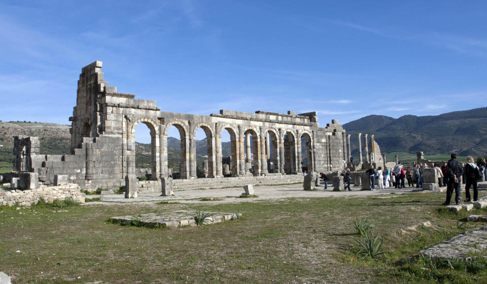 In this Thursday, March 8, 2012 photo, tourists gather around the arches of the Basilica, the main administrative building of Volubilis, Morocco's most famous Roman ruin near Meknes, Morocco. (AP Photo/Abdeljalil Bounhar)
