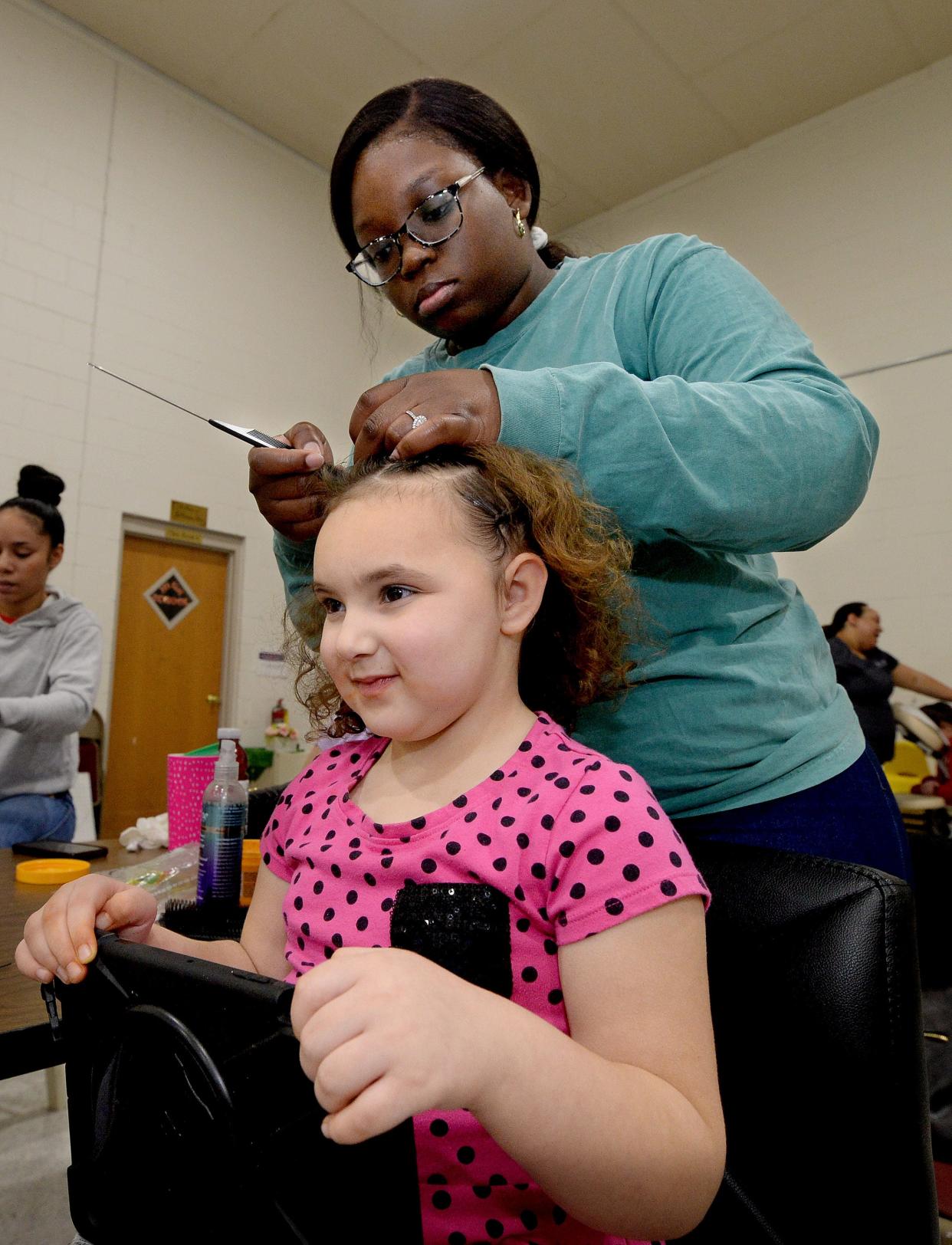 Olivia Schackmann, 4, of Clinton, gets her hair styled by volunteer Jallah Wilson of Springfield at the Pleasant Grove Baptist Church Saturday Dec. 17, 2022.