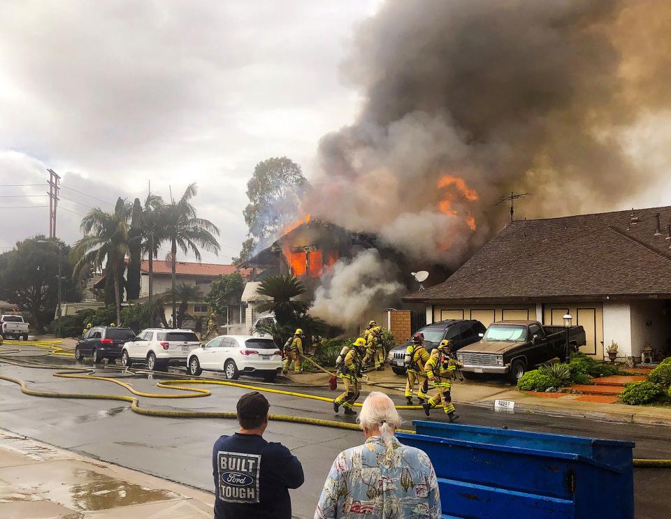 In this Sunday, Feb. 3, 2019 photo, provided by Kyle Vanderheide, Yorba Linda firefighters rush to a home engulfed in flames after a deadly small plane crash in Yorba Linda, Calif.