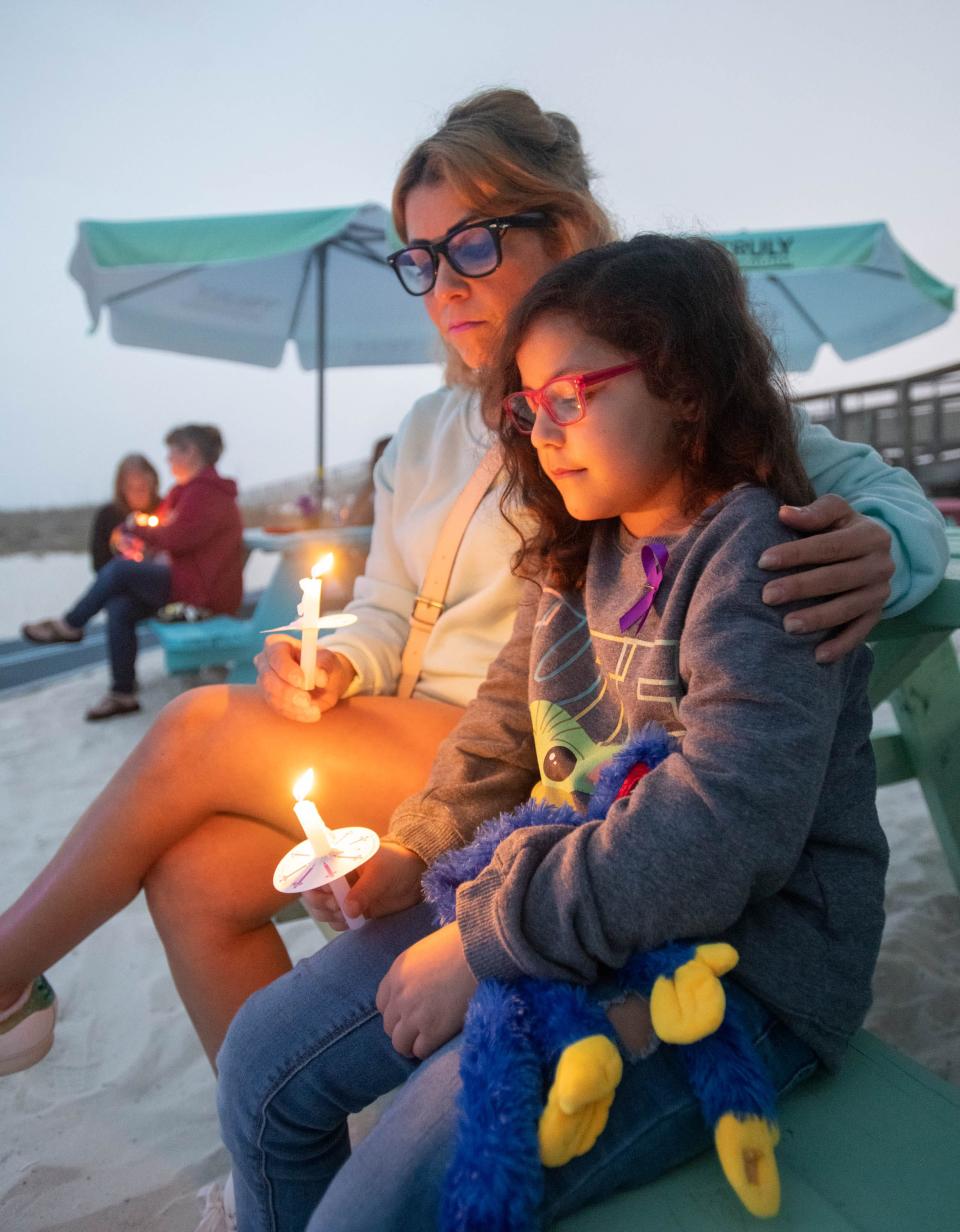 Katherine Shoemaker and her daughter Julianna Hernandez, 8, hold candles during a candlelight vigil in honor of Cassie Carli at Windjammers on the Pier in Navarre Beach on Thursday, Feb. 23, 2023. Dr. Joel Rudman, Florida House of representative for District 3, announced filing a bill dubbed the "Cassie Carli Law" to establish safe zones for custody exchange of children.