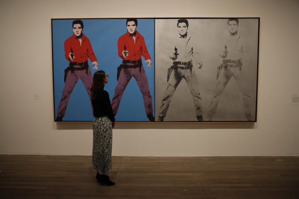 Una representante del Tate Modern, en el centro, posa junto a la obra de Andy Warhol de 1963-1964 "Elvis I and II" durante una presentación a la prensa de la exposición "Andy Warhol" en el museo en Londres, el martes 10 de marzo del 2020. La muestra estará abierta al público desde el 12 de marzo hasta el 6 de septiembre. (AP Foto/Matt Dunham)