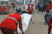 Rescue workers carry away the body of a civilian who was killed in a blast in Mogadishu, Somalia Thursday, Nov. 25, 2021. Witnesses say a large explosion has occurred in a busy part of Somalia's capital during the morning rush hour. (AP Photo/Farah Abdi Warsameh)
