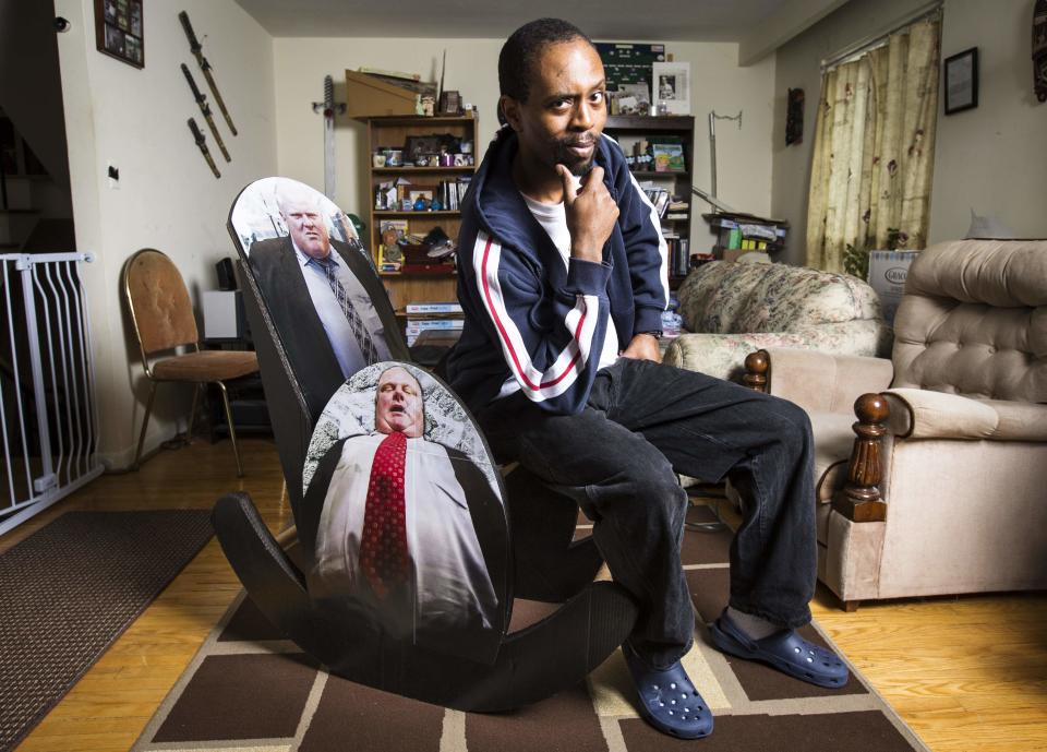 Luanga Nuwame, poses on his "Mayor Rob Ford Crack Rocker", a rocking chair made completely of cardboard materials with pictures of the embattled Toronto Mayor Rob Ford on the back and sides, in Mississauga, December 12, 2013. Nuwame, also known as the "Homemade Game Guru", is an artist who creates things made of cardboard, was inspired to make the chair after Toronto Mayor Ford admitted early last month he had smoked crack cocaine, saying it was probably "in one of my drunken stupors," but he has said he is not an addict. REUTERS/Mark Blinch (CANADA - Tags: POLITICS SOCIETY TPX IMAGES OF THE DAY)