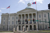 The magnolia flower centered banner chosen Wednesday, Sept. 2, 2020 by the Mississippi State Flag Commission flies adjacent to the American flag in a brisk wind, outside the Old State Capitol Museum in downtown Jackson, Miss. The nine member committee voted to recommend a design with the state flower, now known as the "In God We Trust," flag. That design will go on the November ballot for voters consideration and if approved, it will become the new state flag. (AP Photo/Rogelio V. Solis)