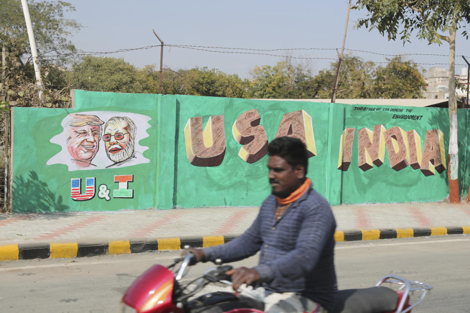 A man rides past a wall painted with portraits of U.S. President Donald Trump and Indian Prime Minister Narendra Modi ahead of Trump's visit, in Ahmadabad, India, Tuesday, Feb. 18, 2020. Trump is scheduled to visit the city during his Feb. 24-25 India trip. (AP Photo/Ajit Solanki)