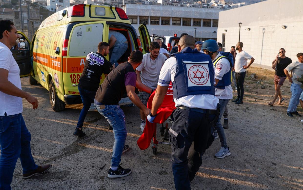 Medics and residents transport casualties of the Hezbollah rocket strike in the town of Majdal Shams in the Golan Heights