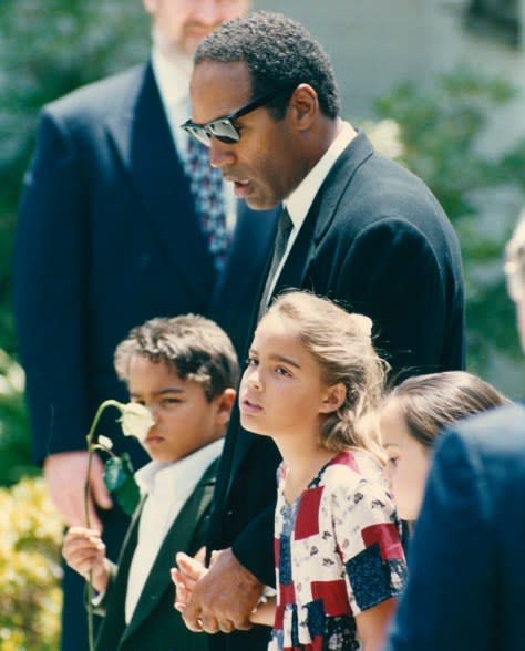 American football player and actor O J Simpson holding hands with his children Justin and Sydney at the funeral of their mother, and his ex-wife, Nicole Simpson Brown following her murder, Los Angeles, June 16th 1994.