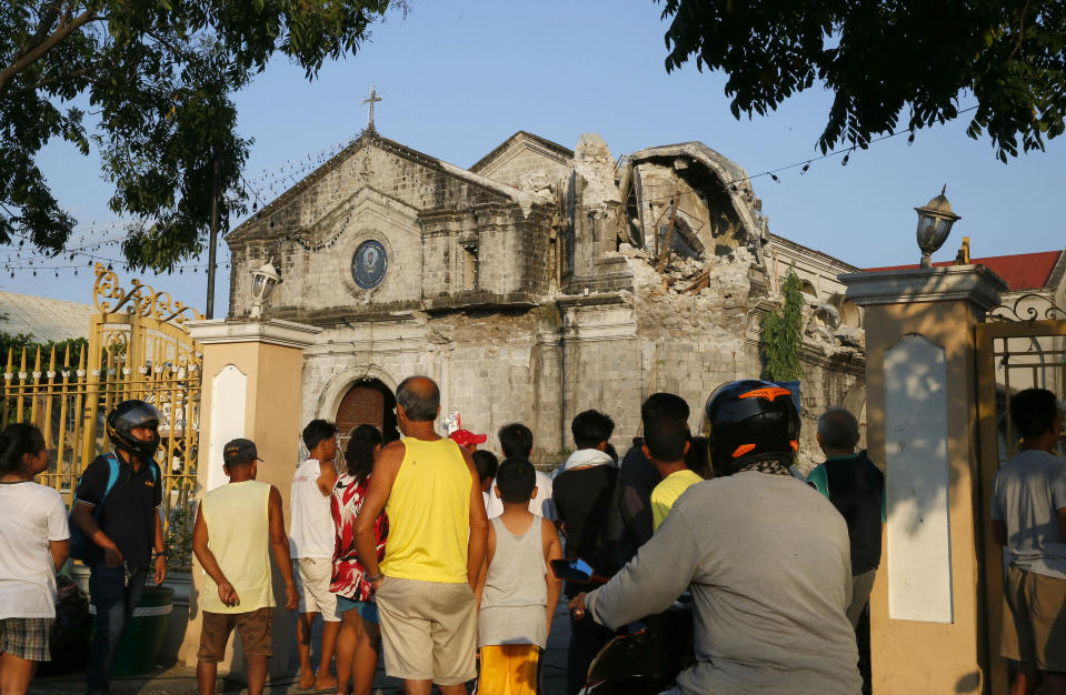 Residents look at the damaged St. Catherine church following a 6.1 magnitude earthquake in Porac township, Pampanga province, north of Manila, Philippines, Tuesday, April 23, 2019. The strong earthquake struck the northern Philippines Monday trapping some people in a collapsed building, damaged an airport terminal and knocked out power in at least one province, officials said. (AP Photo/Bullit Marquez)