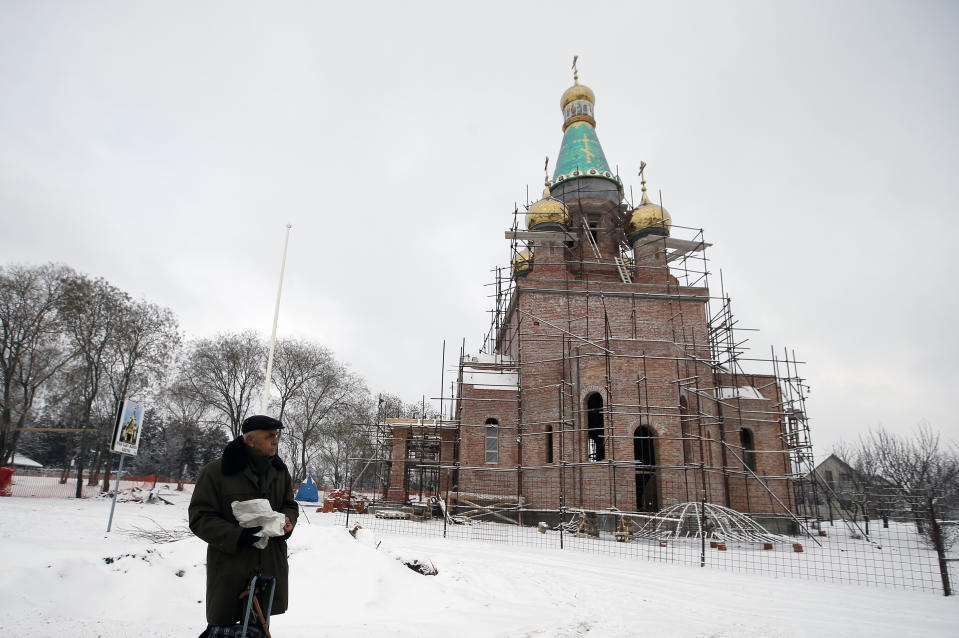 In this photo taken Friday, Jan. 11, 2019, a man walks by the new church under construction designed in the Russian style in the village Banstol in northwestern Serbia. Topped with Russia-style green and gold onion-shaped domes, the church in this tiny village in northwestern Serbia is still under construction but it has already been dubbed ''Putin's church.'' (AP Photo/Darko Vojinovic)