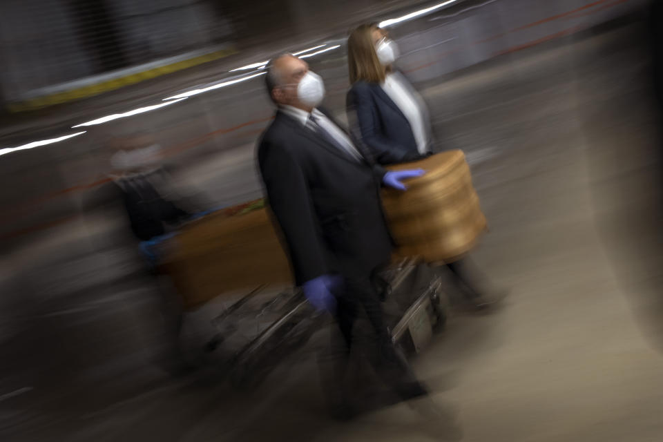 Mortuary service workers carry the coffin of the last COVID-19 victim stored at an underground parking garage that was turned into a morgue, at the Collserola funeral home in Barcelona, Spain. May 17, 2020. A funeral home in Barcelona has closed a temporary morgue it had set up inside its parking garage to keep the victims of the Spanish city's coronavirus outbreak. The last coffin was removed and buried on Sunday. In 53 days of use, the temporary morgue has held more than 3,200 bodies. (AP Photo/Emilio Morenatti)