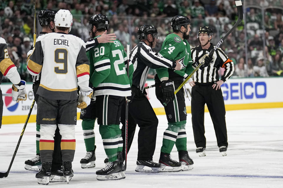 Dallas Stars left wing Jamie Benn, right, is escorted by officials as Vegas Golden Knights' Jack Eichel (9) and Stars' Ryan Suter (20) watch during the first period of Game 3 of the NHL hockey Stanley Cup Western Conference finals Tuesday, May 23, 2023, in Dallas. Benn was issued a cross-checking penalty and a game misconduct. (AP Photo/Tony Gutierrez)