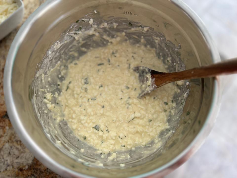 cottage cheese mixture in a metal mixing bowl with a wooden spoon