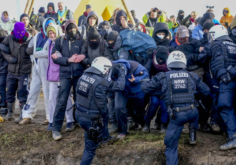 Police officers and protesters clash on a road at the village Luetzerath near Erkelenz, Germany, Tuesday, Jan. 10, 2023. The village of Luetzerath is occupied by climate activists fighting against the demolishing of the village to expand the Garzweiler lignite coal mine near the Dutch border. (AP Photo/Michael Probst)