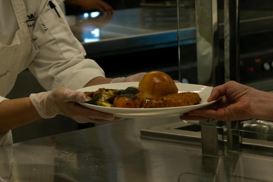 A Del Mar College culinary arts student hands a plate of Japanese-inspired food to a guest at the institution's Oso Creek Campus Thursday, Sept. 21, 2023.