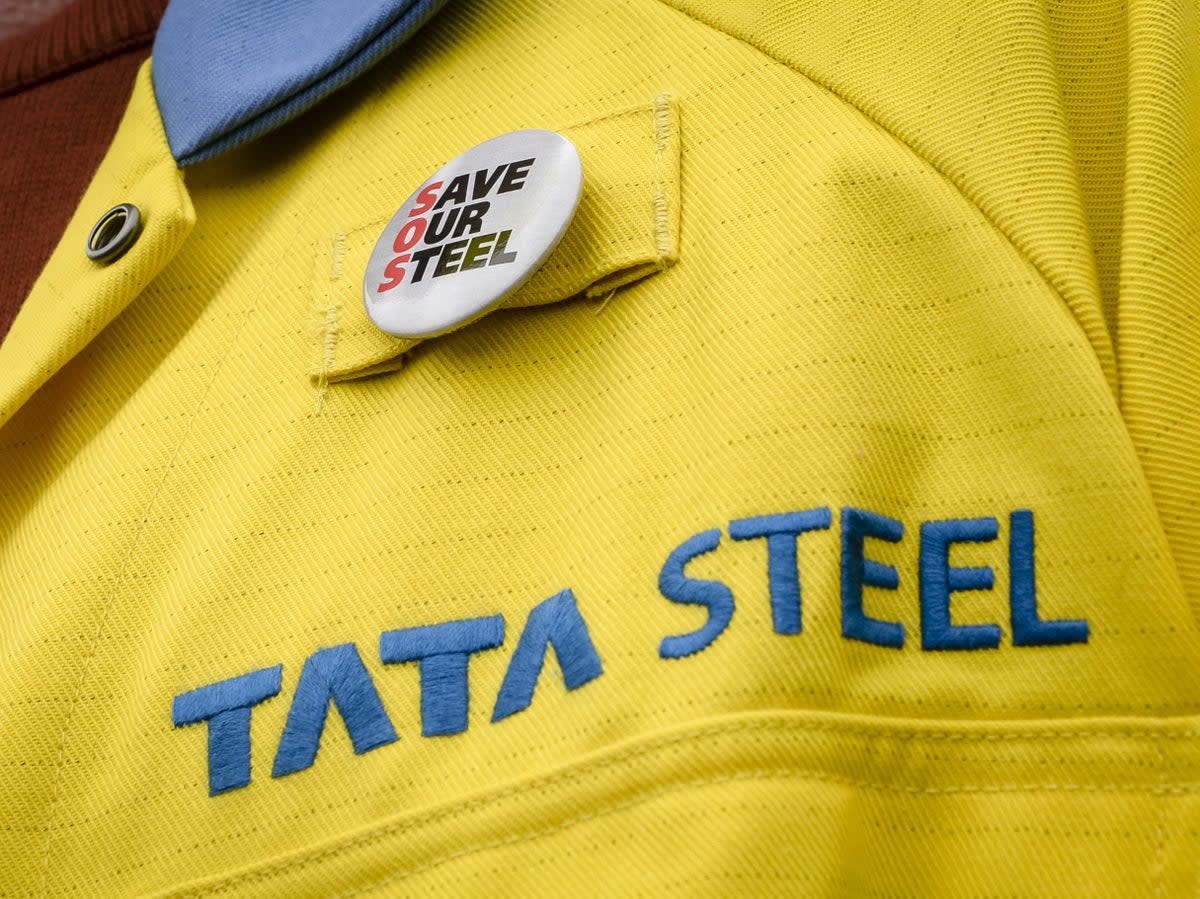 A steelworker wears a badge on his jacket outside the UK’s largest steelworks in Port Talbot (PA)