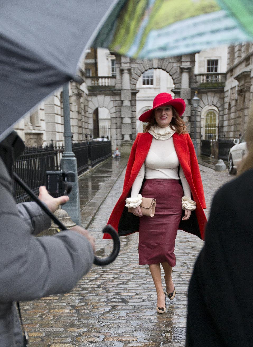 Carmen Negoita a fashion blogger poses for photographs between media umbrellas as rain falls on the first day of London Fashion Week, in London, Friday, Feb. 14, 2014. (AP Photo/Alastair Grant)