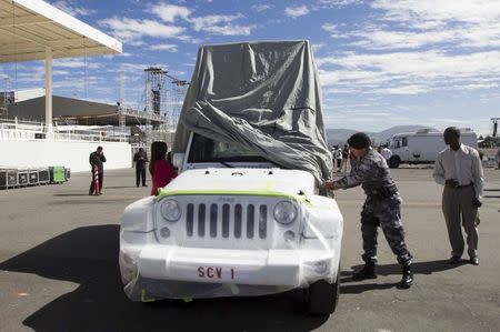 A police officer covers the vehicle to be used by Pope Francis during his visit to Ecuador, in Quito, Ecuador, June 30, 2015. REUTERS/Guillermo Granja