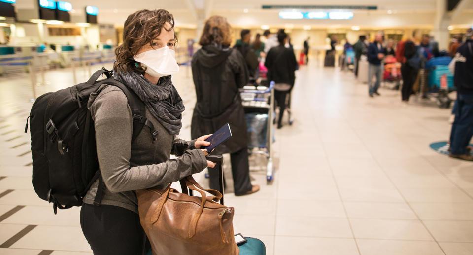 Woman waiting in a long line for a flight wearing a N95 face mask during a global pandemic