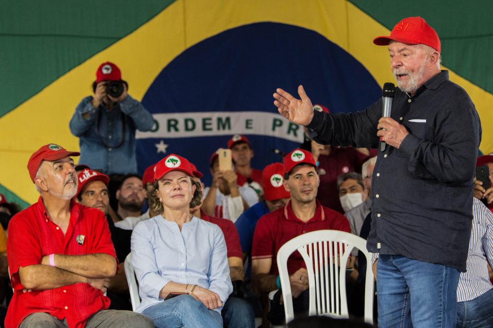 Lula com microfone fala a público com bonés do MST