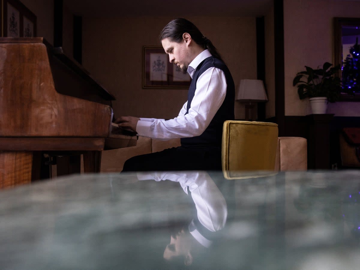 Alexei Antropov, 29, a classical double bassist from Moscow, plays the piano in the lobby of Pino Vere Palace Hotel, where he works as a receptionist in Tbilisi, Georgia (Reuters)