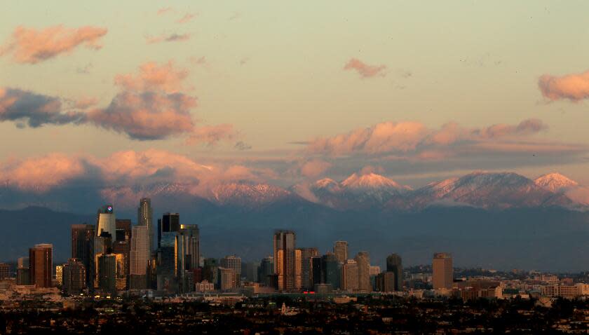 LOS ANGELES, CALIF. - JAN. 1, 2023. The snow-covered San Gabriel Mountains provide a dramatic backdrop for the downtown Los Angeles skyline on Jan. 1, 2023. Rain and snow remain in the forecast for Southern California this week. (Luis Sinco / Los Angeles Times)