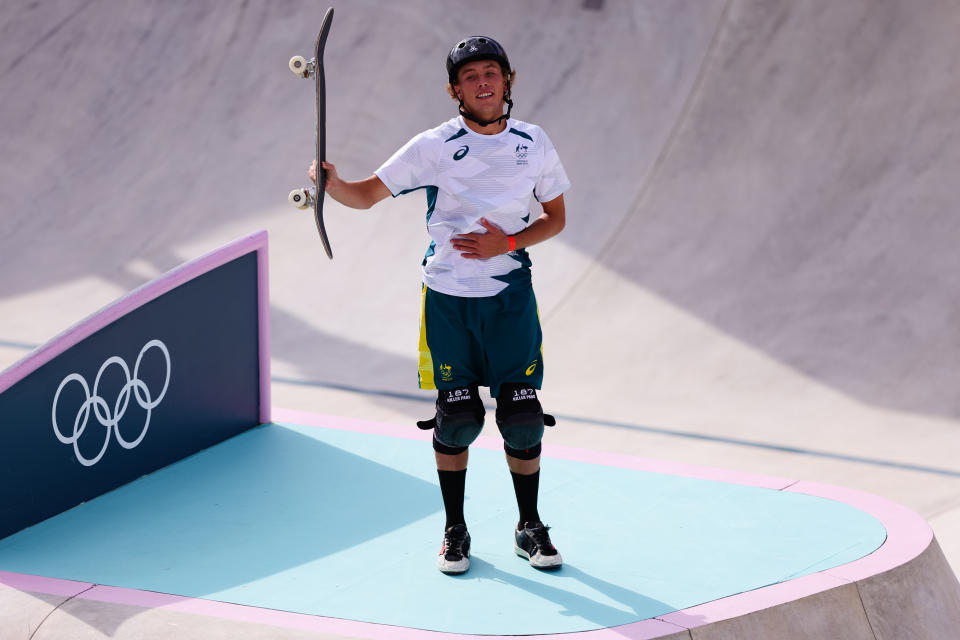 Keegan Palmer triumphantly raises his skateboard.