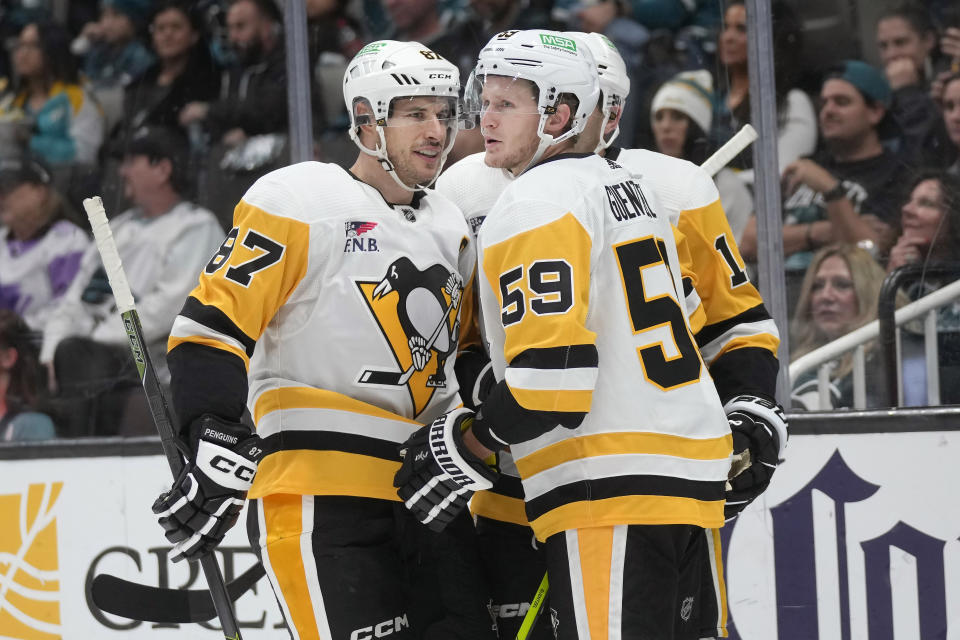 Pittsburgh Penguins left wing Jake Guentzel (59) is congratulated by center Sidney Crosby (87) and right wing Bryan Rust, back, after scoring during the second period of an NHL hockey game against the San Jose Sharks in San Jose, Calif., Saturday, Nov. 4, 2023. (AP Photo/Jeff Chiu)