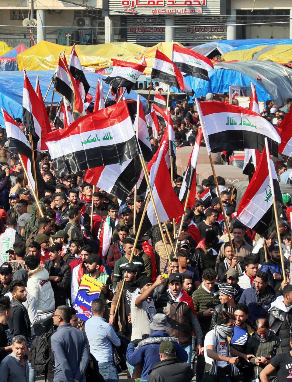 Hundreds of people march inside Tahrir Square carrying national flags and chanting religious slogans in Baghdad, Iraq, Thursday, Dec. 5, 2019. Anti-government protesters at least 15 people have suffered stab wounds in Baghdad's Tahrir Square, the epicenter of their movement, after political parties and Iran-backed militia groups briefly joined them, raising fears of infiltration by authorities. (AP Photo/Hadi Mizban)