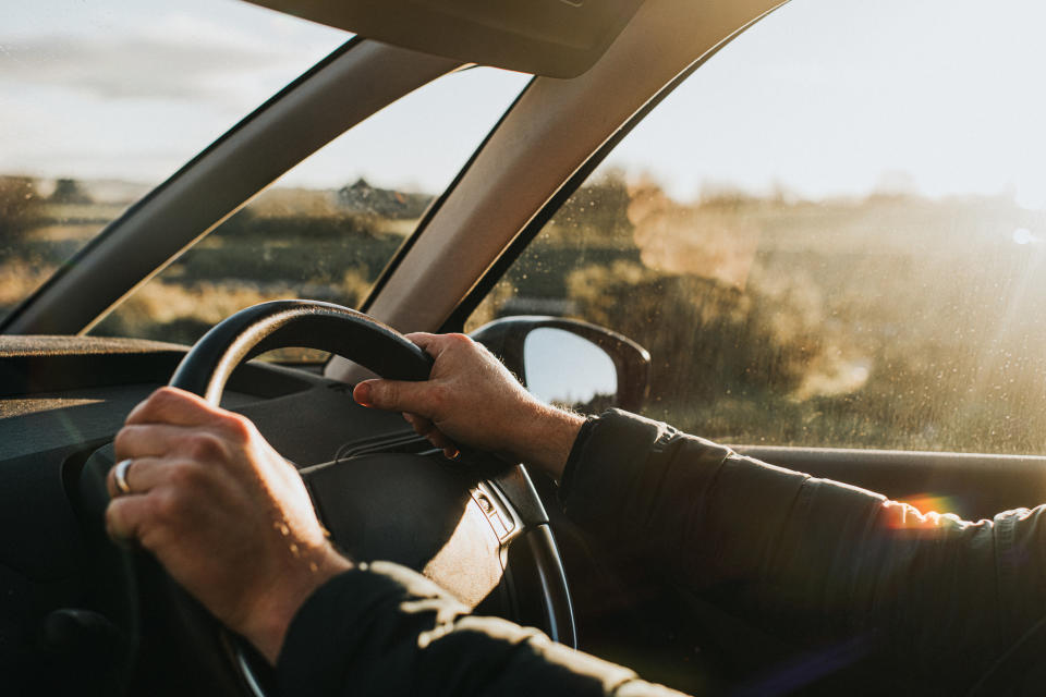 An up-close shot of a person holding a steering wheel driving a car.